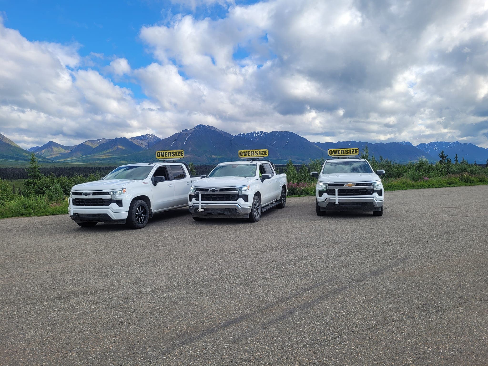 Three Rig Runner pilot cars parked with Alaska mountains behind them